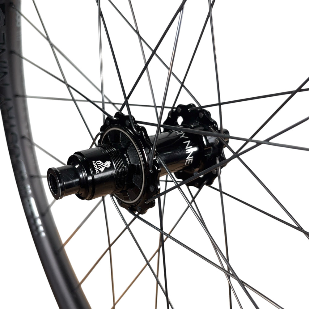 Close-up of a mountain bike wheel hub with black spokes and rim, featuring HYDRA2 branding for trail riding performance.