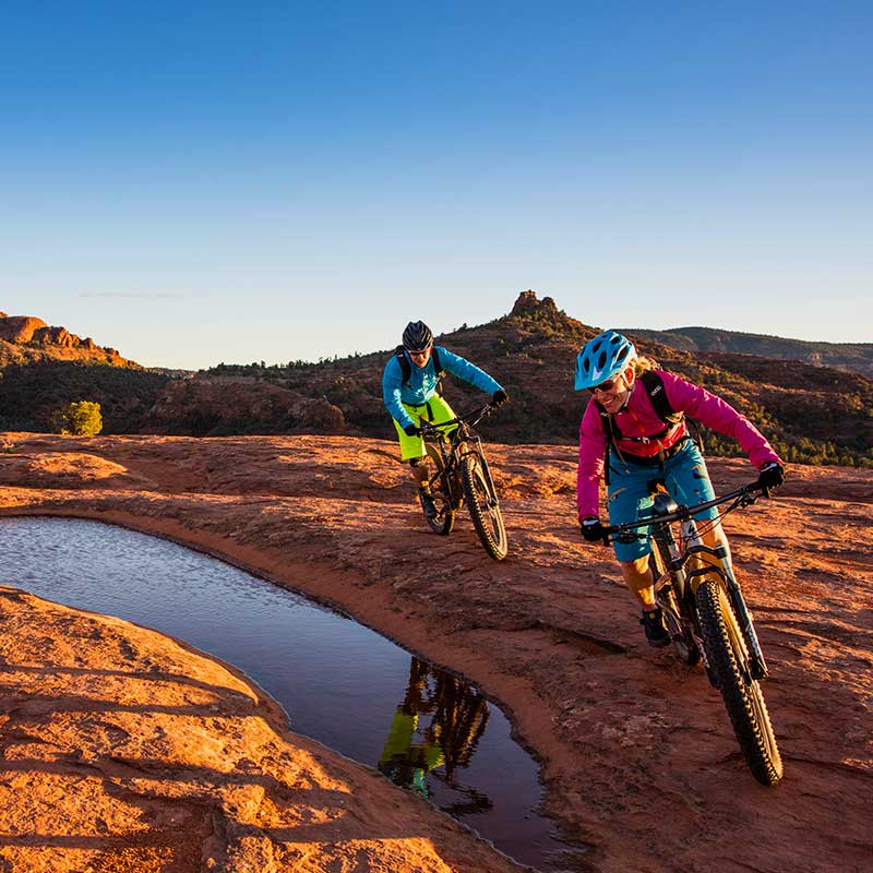 two mountain bike riders on Sedona slickrock with pooled water